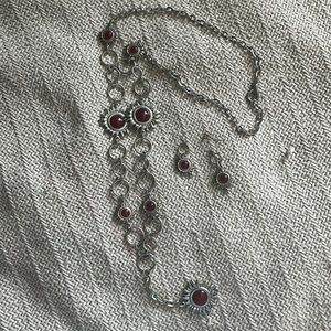 Silver colored long necklace and earrings with red stone sun decorations